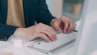 Close-up of hands typing on a computer keyboard in an office setting.